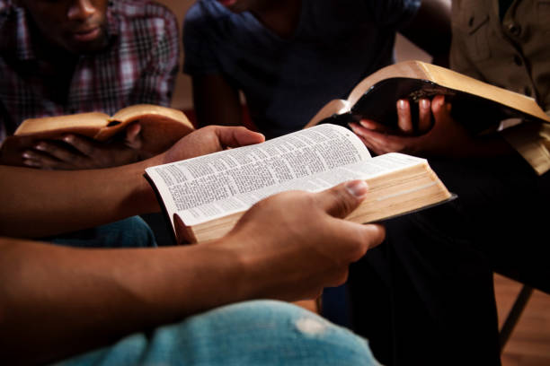 Young adults meeting together in a Bible study.  Focus on the Open Bible.